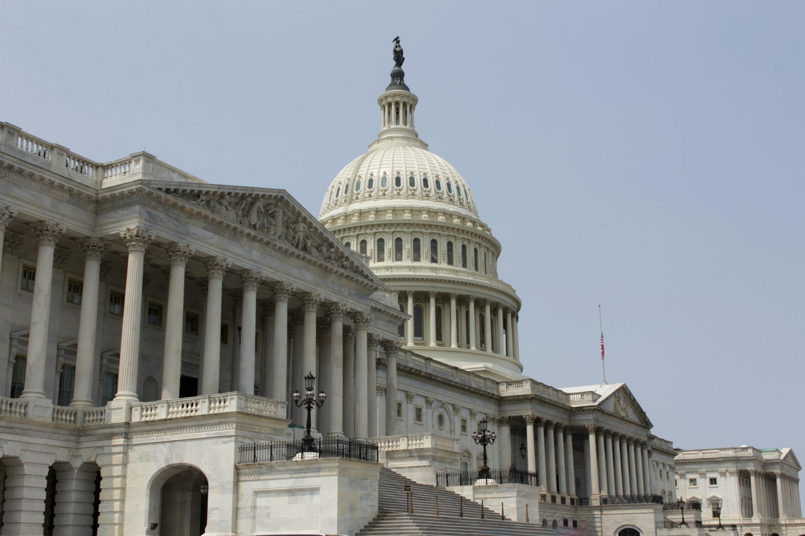 The United States Capitol building in Washington, D.C., featuring its iconic dome, grand columns, and steps leading to the entrance under a clear sky.