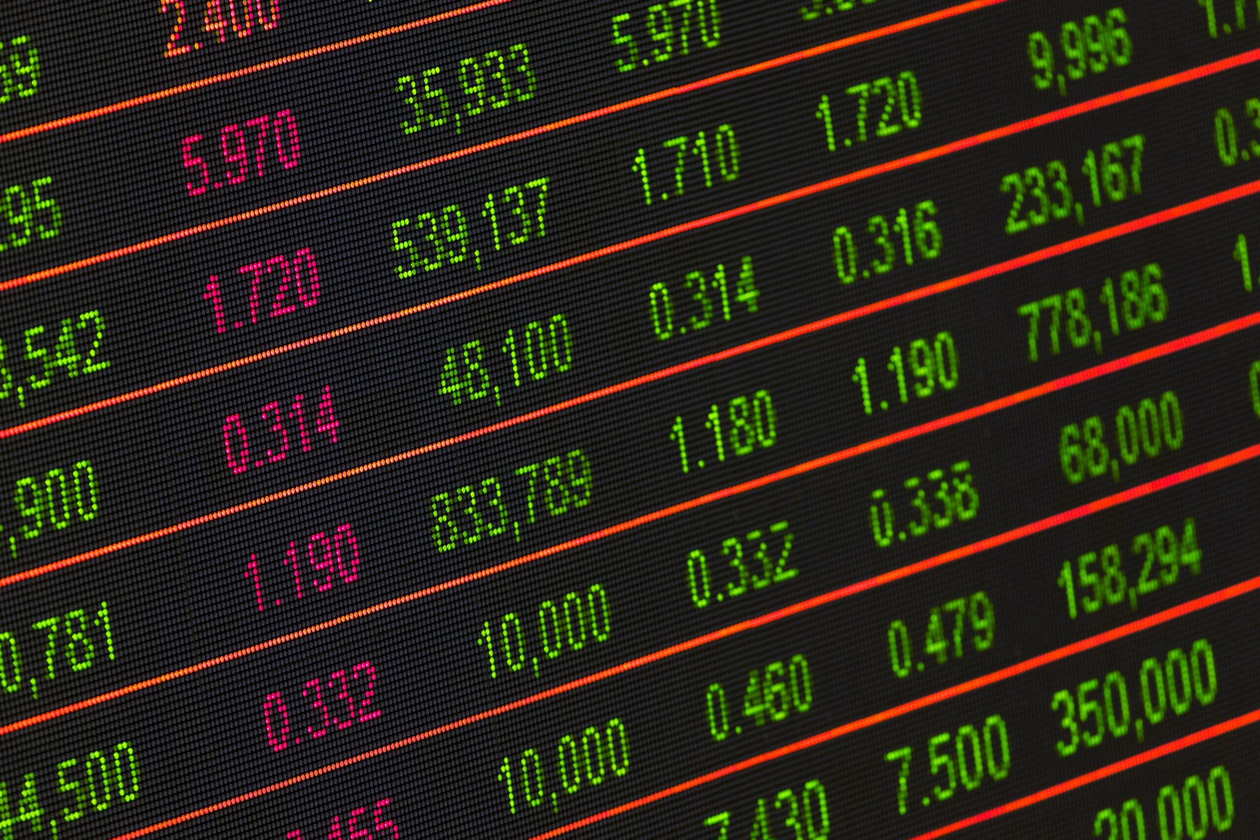 Close-up of a digital stock market display showing rows of numbers in green, red, and pink, representing various financial data such as stock prices and trading volumes.