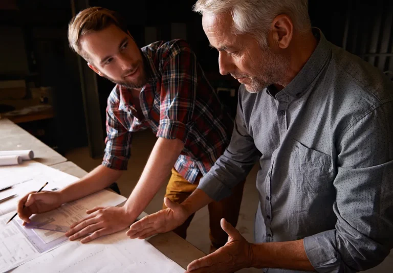 Two generations of business owners reviewing plans together as they prepare for a company transition.