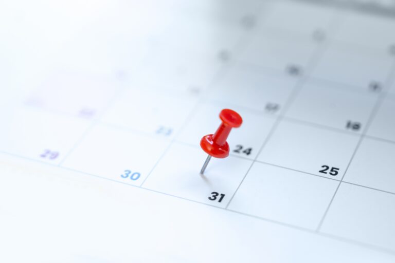 Red pushpin marking the 31st on a calendar, illustrating a year-end tax planning deadline.